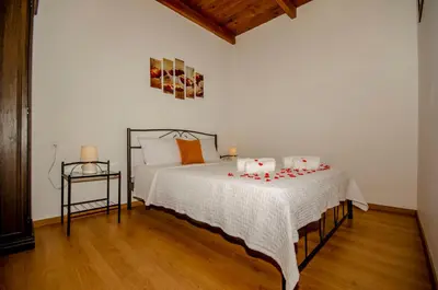 a bedroom with a bed with a white blanket and a table at Trouli Rokka House in Kissamos