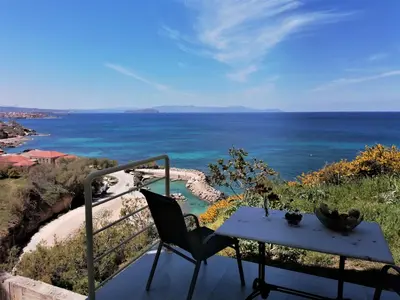 a table and chair on a balcony overlooking the ocean at Emerald Apartment Halepa in Chania Town
