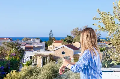 a woman taking a picture of a city at s u e ñ o - studios and apartments, with shared pool in Kato Daratso