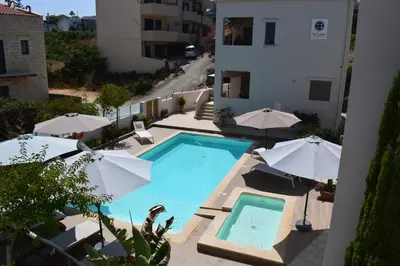 a swimming pool with umbrellas next to a building at Four Seasons Homes in Stalos