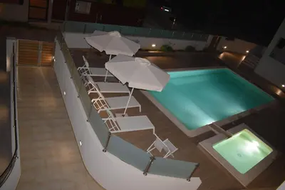 a swimming pool with lounge chairs and umbrellas at Four Seasons Homes in Stalos