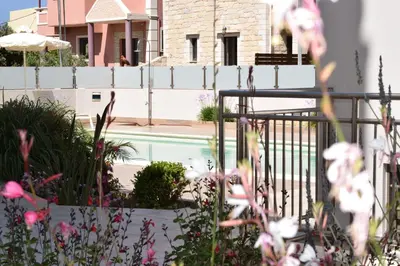 a swimming pool with a white fence and flowers at Four Seasons Homes in Stalos