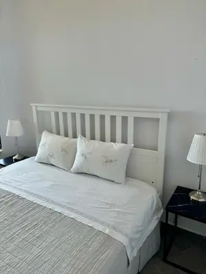 a white bed with two white pillows and two lamps at Venizelos Studios in Plataniás