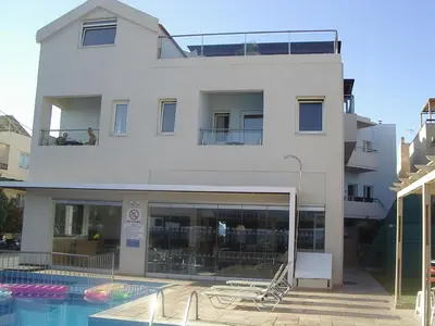 a white building with a swimming pool in front of it at Despina Apartments in Plataniás