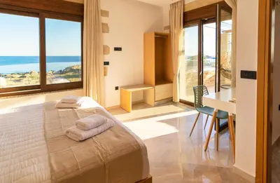 a bedroom with a bed and a desk and windows at Athinais villa in Palaiochóra
