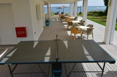a ping pong table on a deck with tables and chairs at Geraniotis Hotel and Resort in Plataniás