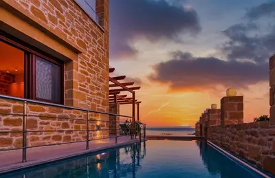 a swimming pool on the side of a building with a sunset at Anma Villa in Palaiochóra