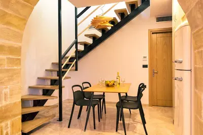 a dining room with a table and chairs and a spiral staircase at Anma Villa in Palaiochóra