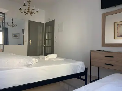 a bedroom with two beds and a dresser and a mirror at Porto Chania in Chania Town