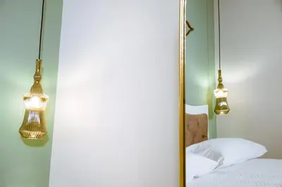 a mirror in a bedroom with two lights and a bed at Konmari Boutique Suites in Chania Town