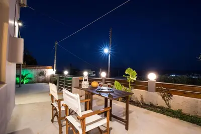 a table and chairs on a balcony at night at M & E Kissamos sea view house in Kissamos