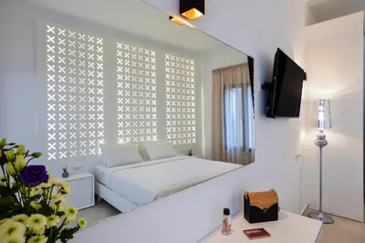 a white bedroom with a bed and a mirror at Elia Portou Luxury Residence in Chania Town