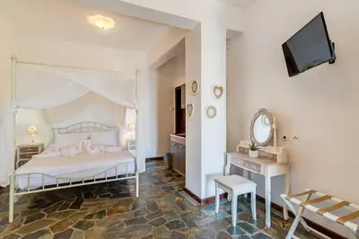 a bedroom with a white bed and a mirror at VENTUS Studios in Khóra Sfakíon