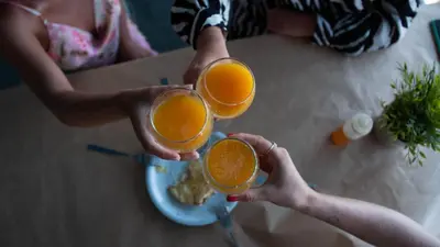 two people holding up two glasses of orange juice at VENTUS Studios in Khóra Sfakíon