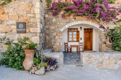an entrance to a stone building with purple flowers at VENTUS Studios in Khóra Sfakíon