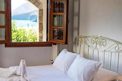 a bedroom with a white bed with a window at VENTUS Studios in Khóra Sfakíon