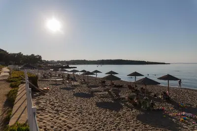 a beach with umbrellas and people sitting on the sand at Nicky Apartments Chania in Chania Town