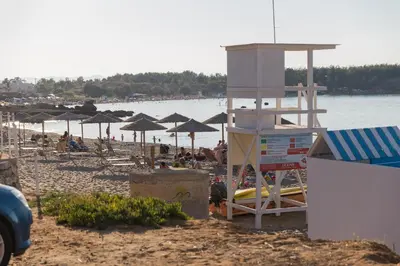 a beach with umbrellas and people on the beach at Nicky Apartments Chania in Chania Town