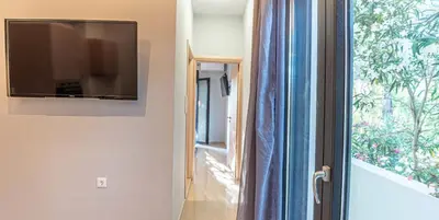 a flat screen tv hanging on a wall next to a window at On the sand 1 in Palaiochóra