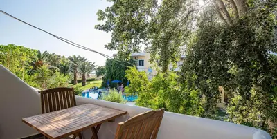 a balcony with a table and chairs and a pool at On the sand 1 in Palaiochóra