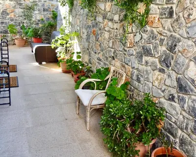 a white chair sitting next to a stone wall at Faros apartment in Sfakiá