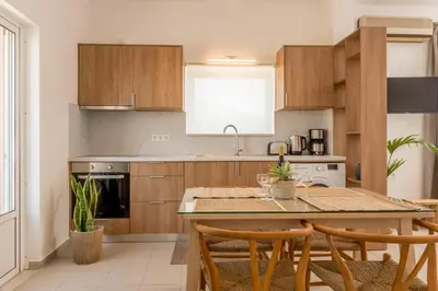 a kitchen with wooden cabinets and a table with chairs at eden of grameno in Palaiochóra