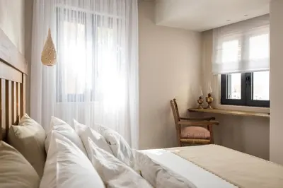 a bedroom with a bed with white sheets and a window at Cretan Soul in Plataniás