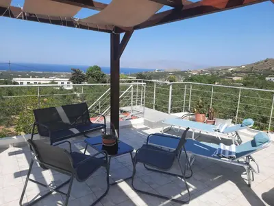 a patio with chairs and a table and an umbrella at George's House between Falasarna and Balos in Kissamos