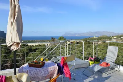 a patio with a table and chairs and the ocean at George's House between Falasarna and Balos in Kissamos