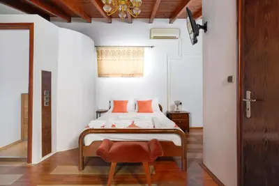 a bedroom with a bed with orange pillows and a chair at Matzi House in Chania Town