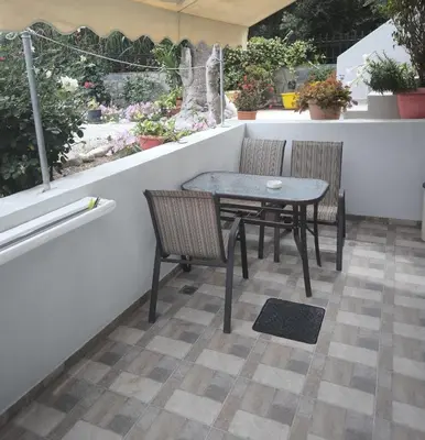 a table and chairs on a balcony with plants at Alexia Rooms in Palaiochóra