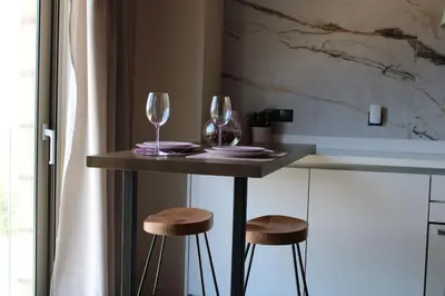 a table with two wine glasses and two stools at INO II Domus POOL by Amigdalokefali Elafonissi in AmigdhalokeFálion