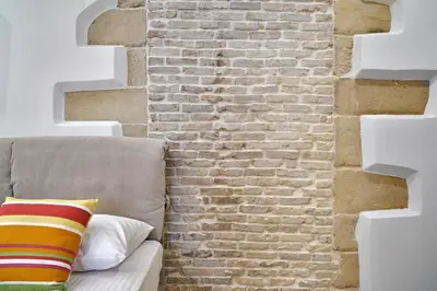 a brick wall next to a couch with a pillow at Semeli Apartment in Kissamos