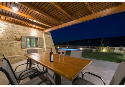a wooden table with a bottle of wine on a patio at Villa Arietta in Kharkhalianá