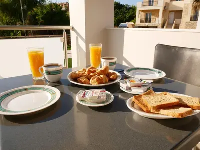 a table with plates of toast and bread and orange juice at Erotokritos Studios near the beach in Agia Marina Nea Kydonias