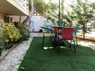a patio with a table and chairs on grass at The Green Apartment, 1 min walk from Kalamaki beach in Kalamaki Chanion
