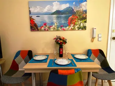 a table with chairs and a painting on the wall at The Green Apartment, 1 min walk from Kalamaki beach in Kalamaki Chanion