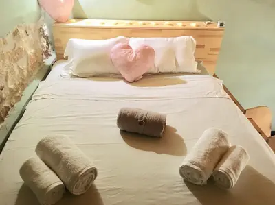 a bed with four pillows and a pink heart and towels at Maria`s Peaceful Nest in Chania Town