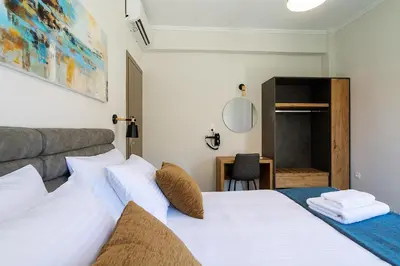 a bedroom with a white bed and a desk at Bitsakis Family II - Paleochora Luxury House in Palaiochóra
