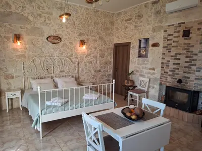 a bedroom with a bed and a table and a fireplace at La casa de Ioanna in Kissamos