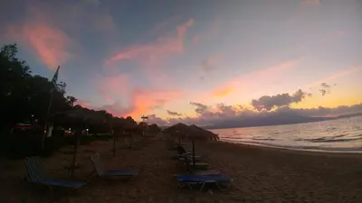 a group of chairs and umbrellas on the beach at sunset at Camping Mithimna in Kissamos