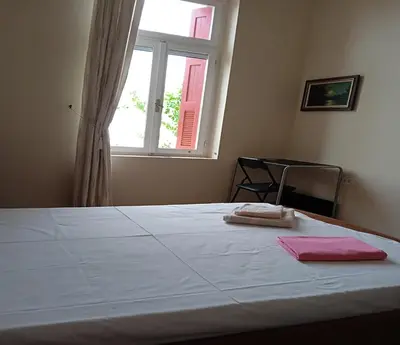 a bedroom with a white bed with a window at Kissamos Grandfather's House in Kissamos