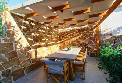 a patio with a table and chairs under a stone wall at Bitsakis Family - Paleochora Luxury Villa in Palaiochóra