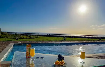 a table with two glasses of orange juice next to a swimming pool at Villa Kore Elafonissi in Ãyios FÃ³tios