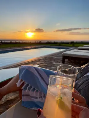 a person holding a glass of drink with the sunset at Villa Kore Elafonissi in Ãyios FÃ³tios