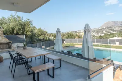 a patio with a table and chairs and a swimming pool at Horizon Villa Almyrida in Almirida