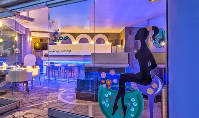 a window of a restaurant with a woman sitting on a chair at Castle Suites Hotel in Plataniás