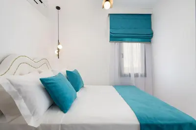 a bed with blue and white pillows and a window at Castello Luxury Residence with Private Jacuzzi in Chania Town