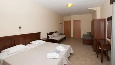a bedroom with two white beds and a piano at Anopoli Rooms in Anopoli Sfakion