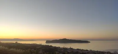 an island in the middle of the ocean at sunset at Wish Sea & Mountain View in Stalos